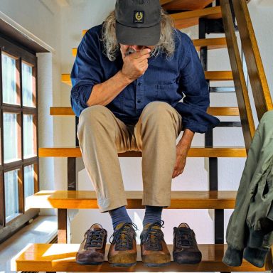 Schuhtypen Ein Mann sitzt auf einer Treppe und betrachtet zwei Paare von Schuhen.