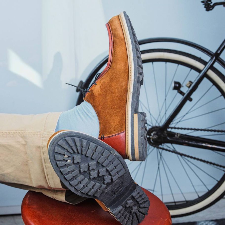 Braune Schuhe mit grober Sohle, daneben ein Fahrrad in Hintergrund.