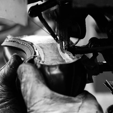 Herstellung Eine Hand näht mit einer Nähmaschine an einem Lederstück.